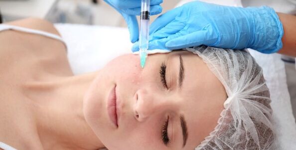 The beautician performs a facial skin rejuvenation procedure with plasma